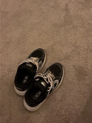 Svarta sneakers med vita detaljer - Säljer ett par svarta sneakers med vita detaljer och vita snören 