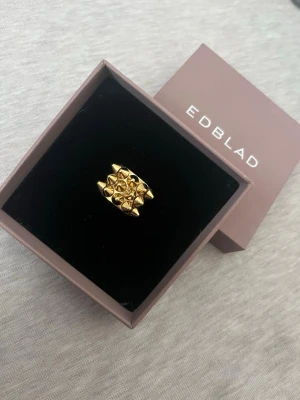 Guldfärgad statementring från Edblad spike ring  - Snygg guldfärgad ring från Edblad med coola pyramidformade detaljer som ger en edgy och modern look. Storlek 16,00 och är helt ny inte används eftersom det var en present därför får man även boxen till 