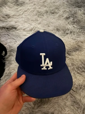 Blå LA Dodgers keps från New Era - Säljer en klassisk blå LA Dodgers keps från New Era med vit broderad LA-logga framtill och New Era-logga på sidan. Är självklart öppen för prisförslag och säljer fler varor så köper du många får du också mängdrabatt. Obs säljes som på bild.