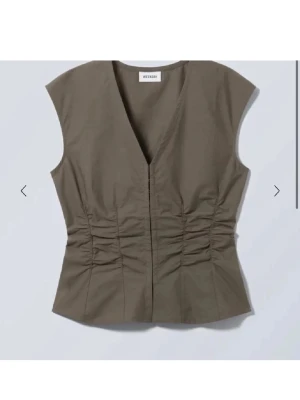 Olivgrön v-ringad topp från Weekday - Snygg olivgrön topp från Weekday med v-ringning och markerad midja med rynkade detaljer. Knappt använd!!!💓💓