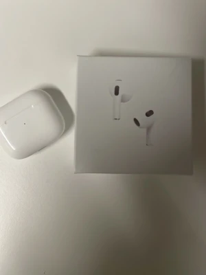 Apple AirPods 4 med laddningsetui - Säljer ett par vita Apple AirPods 4 med trådlöst laddningsetui. Snygg och kompakt design i blank plast, perfekt för dig som vill ha smidiga in-ear hörlurar med grymt ljud och enkel anslutning till iPhone eller andra Apple-enheter. Originalförpackning medföljer.