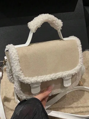 Beige handväska med fuskpälsdetaljer - Stilren beige handväska med mjuka fuskpälsdetaljer längs kanterna och på handtaget. Väskan har ett lock, vita spännen och axelrem i vitt. 