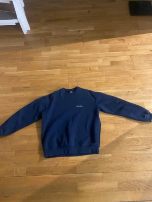 Mörkblå sweatshirt från Sweet SKTBS - Mörkblå sweatshirt från Sweet SKTBS med broderad logga på bröstet. Klassisk rund halsringning och ribbade muddar vid ärmslut och nederkant. Perfekt för en avslappnad streetwear-look. Pris kan diskuteras.