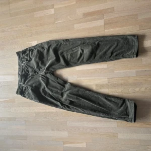 Mörkgröna manchesterbyxor - Säljer ett par mörkgröna manchesterbyxor med raka ben och klassisk femficksdesign. Byxorna har en avslappnad passform och är tillverkade i mjuk manchester som ger en skön vintagekänsla. Perfekta för dig som gillar retrostil och vill ha något bekvämt.