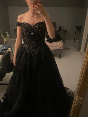 Svart glittrig balklänning offshoulder - Magisk svart långklänning med glittriga detaljer och offshoulder-modell. Klänningen har en markerad midja och vid kjol som ger en riktigt elegant siluett. Perfekt för bal eller andra speciella tillfällen. Materialet känns lyxigt och skimrar snyggt i ljuset. Märket är Layla K och originella priset var 5300kr. Denna är xs och jag är cirka 165 cm!