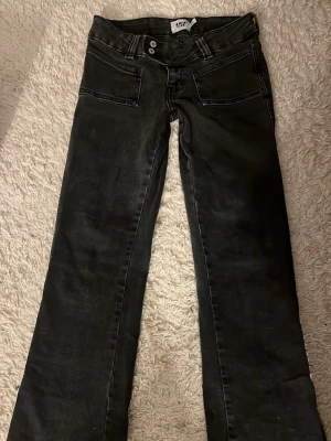 Svarta bootcut jeans, låg midjat  - Säljer ett par svarta bootcut jeans med låg midjat och raka ben som slutar i en lätt utsvängning. Jeansen har två framfickor och är tillverkade i ett mjukt denimtyg. Perfekta för en trendig och avslappnad look.