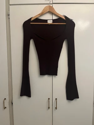 Vinröd ribbad långärmad topp - Trendig vinröd ribbad topp med lång ärm och snygg v-ringning. Figurnära passform och stretchigt material som ger en smickrande siluett. Perfekt till jeans eller kjol för en cool look.