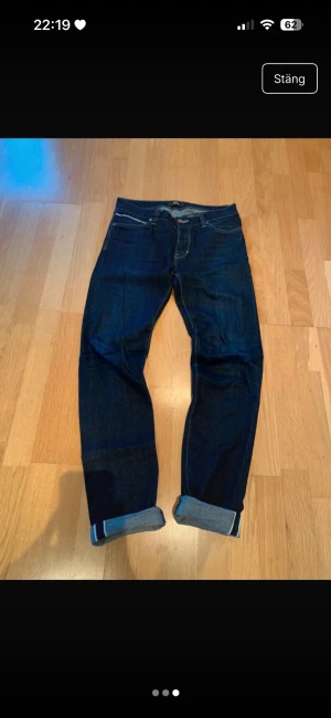 Mörkblå selvedge jeans från Neuw - Säljer ett par mörkblå jeans från Neuw med klassisk femficksmodell och kontrastsömmar. Jeansen har upprullade benslut och är tillverkade i ett slitstarkt denimtyg. Perfekta för dig som gillar en enkel och stilren look.