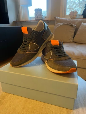 Blåa Phillipe modells - Säljer ett par blå Phillipe modells med orange detaljer. Skick: 8/10✅, längst framm på högra skon sticker en liten del ut annars är de i bra skick. Nypris: ungefär 2500kr, mitt pris: 549kr✅ Original låda och dustbag följer med👍🏼Hör av er vid frågor!🙌