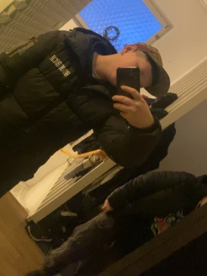 Svart pufferjacka från Hoodrich - Säljer en svart pufferjacka från Holzweiler med hög krage och huva. Jackan har en tydlig logga på bröstet och dragkedja framtill. Perfekt för kalla dagar och riktigt snygg streetstil.