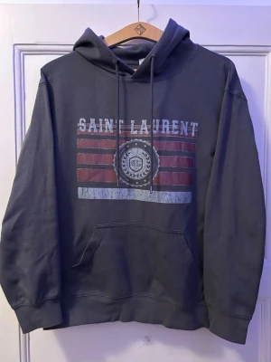 Grå hoodie - Snygg mörkgrå ysl hoodie. Skriv om du har frågor. Pris är inte hugget i sten då jag helst vill få bort den. LÄGG BUD!