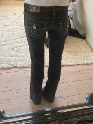 True Religion jeans - Säljer ett par jättesnygga vintage true religion jeans. Köpta från vintage & friends för 1300kr. Dom är i en mörk grå färg och i storlek 25, ärväldigt low waist!Säljer då dom är lite för korta (jag är 168cm med långa ben), har sprättat upp jeansen längst ner, som man kan se på bilderna🫶🏻 skriv om ni undrar något 🥰