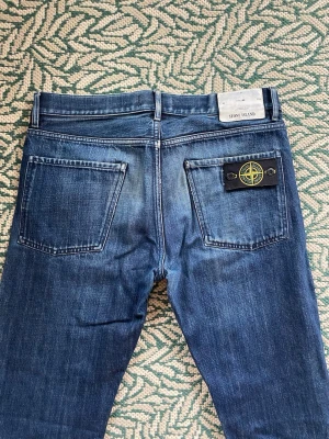 Stone Island Jeans W32/L34 - Mörkblå jeans från Stone Island med den klassiska Stone Island-badgen på höger bakficka. Storlek W32/L34. Säljer då jag inte använder.