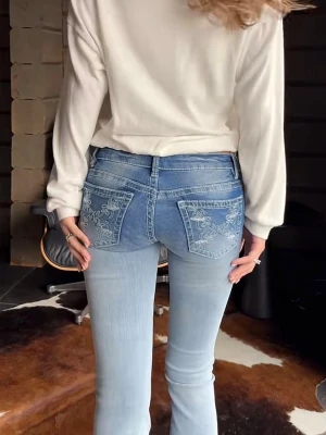 Ljusblå bootcut jeans Gina tricot - Säljer ett par ljusblå bootcut jeans med klassisk femficksdesign och lätt slitna detaljer. Jeansen har hög midja och utsvängda ben, vilket ger en retroinspirerad look. Perfekta till sneakers eller boots för en avslappnad stil.