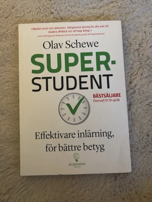 Superstudent av Olav Schewe - Har ett halvbortskrapat klistermärke på baksidan. Boken 'Superstudent' av Olav Schewe hjälper dig att plugga smartare och få bättre betyg. Omslaget är vitt med grön och svart text samt en klocka med en grön bock. Perfekt för dig som vill förbättra dina studietekniker och nå högre resultat.