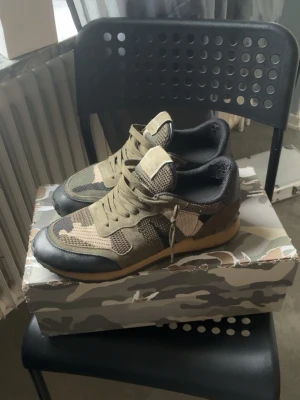 Valentino Rockrunners - Snygga sneakers från Valentino med camomönster i olika nyanser av grönt, beige och svart. Skorna har mesh och mockadetaljer, svarta läderpartier vid tån och en beige sula. Som det syns i bilderna är skorna använda i ca 1-2 månader men fortfarande i väldigt bra skick för användningen. Allting OG som jag fick med när jag fick skorna nya med följer såklart. Mvh!!! Storlek 43 men passar till 44!!! Såklart äkta med!!!