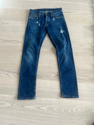 Mörkblåa grim Tim nudie jeans - Mörkblåa grim tim nudie jeans i storlek W28 L30 ett par snygga slitningar