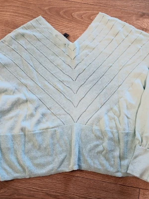 Ljusgrön stickad tröja från Esprit - Snygg ljusgrön stickad tröja från Esprit med V-ringning och diskreta ränder i ett V-format mönster. Tröjan har bred ribbad mudd nedtill och vid ärmsluten. Perfekt för dig som gillar en enkel men stilren look.