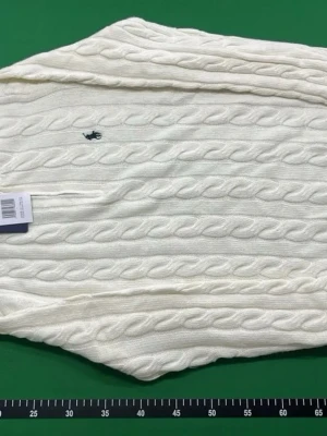 Vit kabelstickad tröja Ralph Lauren - Kabelstickad vit tröja från Ralph Lauren med klassisk broderad logga på bröstet. Tröjan har rund halsringning och är tillverkad i ett mjukt, tunt material som passar perfekt till lager-på-lager. Snygg och tidlös design med ribbade muddar.