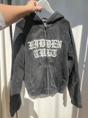 Gråsvart Hidden Cult mjukisset komplett - Säljer mitt Hidden Cult mjukisset. Har dessvärre fått ett hål på bakre benet på höger sida från att ha klivit på den. Även liten skråma på vänstra oxå. Annas är allt i toppskick 🤩zippen går att dra upp hela vägen, båda plaggen är i storlek Small