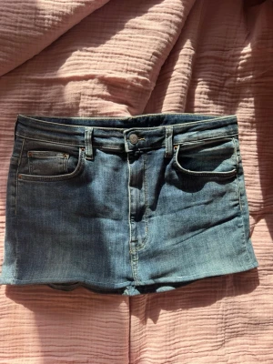 Blå jeanskjol med fem fickor - Säljer en klassisk blå jeanskjol i kort modell med fem fickor och bälteshällor. Kjolen har knapp och dragkedja framtill och är gjord i ett slitstarkt denimtyg. Perfekt för dig som gillar en enkel och tidlös stil. sytt om sjölv 💞