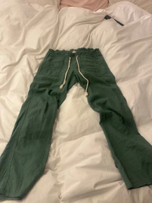 Gröna linnebyxor från Roxy - Säljer min gröna Roxy linnebyxor då de har blivit för korta för mig, de är u bra skick bara att ena snöret har åkt upp så jag har flätat det själv (inget man tänker på när man har på sig dem) jag är 167 och de är precis för korta för mig. De är hela vid hälarna och sparsamt använda. Köpte de för 500!
