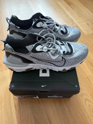 Nike D/MS/X grå sneakers - Snygga Nike D/MS/X sneakers i grått meshmaterial med svarta och vita detaljer. Skorna har en sportig design med synlig sula, stora snörhål och tydlig Swoosh-logga på sidan. Perfekta för dig som gillar streetwear och modern stil. Helt nya använd max 5 gånger. Pris går att diskutera.