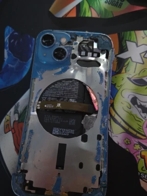 Blå iPhone 13 - Säljer en blå iPhone med dubbla kameror och A15 Bionic chip. Baksidan är i aluminium och glas, och insidan visar batteriet och komponenter. Perfekt för dig som gillar att meka med teknik eller behöver reservdelar till din iPhone. Skalet är bucklat, batteriet är trasigt, den har ingen skärm, vet ej om den startar med nytt batteri/skärm.