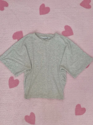 Ljusgrå basic t-shirt - Lager 157 - En enkel ljusgrå t-shirt med rund hals och korta ärmar. T-shirten har en loose passform och är tillverkad i mjuk bomull, perfekt för en avslappnad stil.