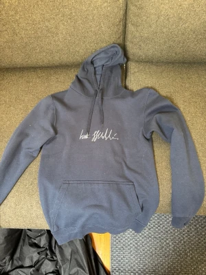 Mörkblå hoodie från Isak Hudén - Mörkblå hoodie med vit brodyr på bröstet och stort vitt tryck på ryggen. Klassisk känguruficka framtill och justerbar huva med snören. Perfekt för en avslappnad och stilren look. Den har hans signatur skrivet över bröstet och hans initsialer ”IH” på ryggen. Exakt modell görs inte längre men när jag fick den så var nypris ca 900kr.  Jag kan ändra mig om priset vid en snabb afär.