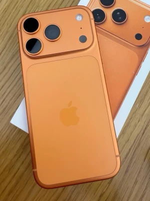 Orange iPhone med dubbla kameror - Snygg orange iPhone med två stora kameralinser och en stilren baksida i aluminium. Telefonen har Apples klassiska logga och rundade hörn. Perfekt för dig som vill sticka ut med en unik färg och modern design.