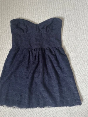 Mörkblå spetsklänning  - Jättesöt mörkblå spetsklänning, utan axelband. Bandeuklänning