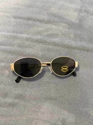 Ovala solglasögon  - Snygga ovala solglasögon med tunn silverfärgad metallbåge och svarta linser. Skalmarna är också i metall med svarta ändar. Klassisk och stilren design som passar till många looks. UV400-skydd för extra säkerhet i solen. Kom gärna med prisförslag 