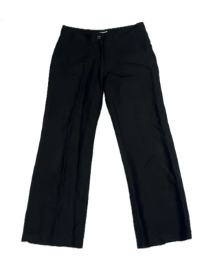 Svarta raka linnebyxor - Svarta kostymbyxor i linnetyg med vida ben och normal midja/midwaist. Byxorna har klassisk passform och stängs med knapp och dragkedja framtill. Tunna i tyget men inte genomskinliga. Märke: Joy, Storlek: 38. Midjemått: 32 tum och Innebenslängd: 31 tum