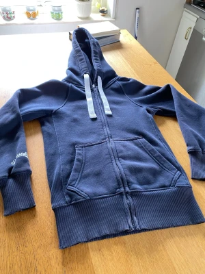 Mörk blå Russemerch zip-tröja - Jag säljer en mörkblå Russemerch tröja i storlek XXS, detta pga att den är för liten för mig. Den är i princip helt ny, köpt för endast några veckor sedan, inga hål, inget slitage, inget missfärgning. Passar både killar och tjejer och är en tröja av väldigt bra kvalitet. Kom gärna med meddelanden angående tröjan om ni är sugna att köpa!☺️