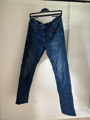G star straight - Snygga mörkblå jeans med rak passform och klassisk femficksdesign. Jeansen har normal midja och är tillverkade i denim med kontrastsömmar. Perfekta för en avslappnad och stilren look.
