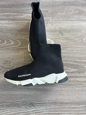 Svarta  Speed sneakers - Säljer ett par svarta  Speed sneakers med vit chunky sula och stickad ovandel. Skorna har en strumpliknande passform och tydlig logga på sidan. Perfekta för dig som gillar streetwear och vill ha något bekvämt och stilrent.