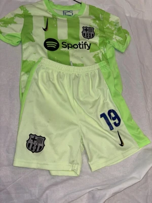 Barcelona matchställ Lamine Yamal #19 - Säljer ett Barcelona matchställ med tröja och shorts i ljusgrönt och neongrönt. Tröjan har tryck med Spotify-logga, klubbmärke och Lamine Yamal #19 på ryggen. Shorts med klubbmärke och nummer 19. Tillverkat i lätt, andasvänligt material.