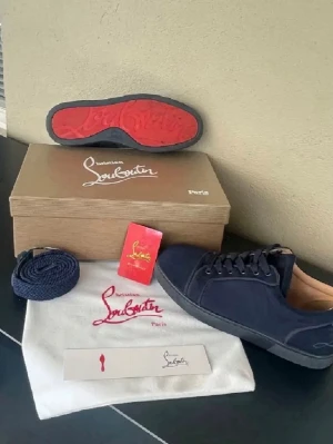 Mörkblå sneakers från Louboutin - Snygga mörkblå sneakers från Christian Louboutin med klassisk röd sula och diskret logga på sidan. Skorna har lågt skaft, svarta skosnören och ovandel i textil. Perfekta för dig som vill ha en stilren och exklusiv look. Använda 2 gånger, säljer de för att de är lite små för mig!