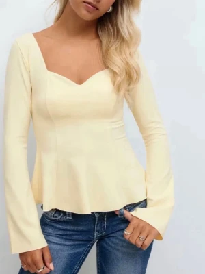 Ljusgul långärmad topp med v-ringning - Trendig ljusgul topp med lång ärm och snygg v-ringning. Modellen har en lätt utsvängd nederdel och figurnära passform upptill. Perfekt att matcha med jeans för en stilren look.