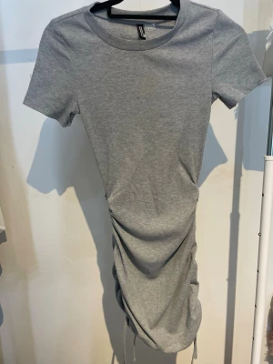 Grå klänning - En grå klänning från H&M, storlek XS. Dragsko på sidorna av klänningen.