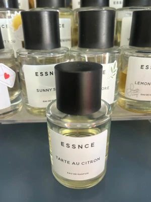 ESSNCE Tarte au Citron parfym - Fräsch parfym från ESSNCE med doft av citronpaj. Flaskan är cylindrisk i genomskinligt glas med svart matt kork och vit etikett med minimalistisk design. Perfekt för dig som gillar fräscha och sötsyrliga dofter.