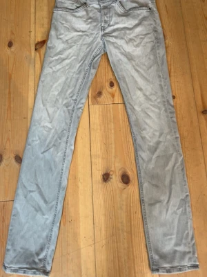 Ljusgrå jeans från dondup - Säljer ett par ljusgrå jeans med rak passform och klassiska fem fickor. Jeansen har en enkel design med kontrastsömmar och är tillverkade i denim. Perfekta för dig som gillar en clean och stilren look.