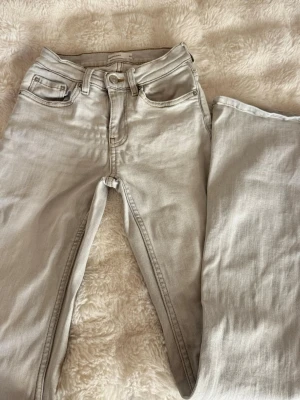 Gina tricot bootcut jeans - Säljer ett par ljusgrå bootcut jeans . Jeansen är mid-low waist och är tillverkade i ett mjukt denimtyg. Perfekta för en avslappnad och stilren look.