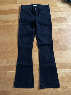 Svarta bootcut jeans mid waist - Svarta bootcut jeans mid waist som även har en design på bakfickorna från gina tricot young! Använt bara 1-2 gånger😚