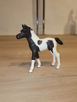 Svartvit hästfigur från Schleich - Säljer en svartvit hästfigur från Schleich med fina detaljer. Figuren har realistisk form och tydliga färgskiftningar mellan svart och vitt. Perfekt som dekoration eller leksak för dig som gillar hästar.