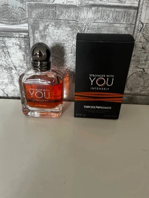 Stronger With You Intensely parfym - Stronger With You Intensely från Emporio Armani är en parfym med varm, amberfärgad vätska i en elegant glasflaska med rundad silverfärgad kork. Förpackningen är svart med kopparfärgade detaljer och tydlig logga. Flaskan rymmer 50 ml. men är ungefär 45 ml kvar