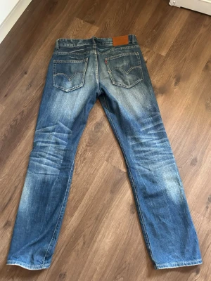 Levis Bootcut jeans 602 - Säljer ett par blå slim Bootcut Levis. Jeansen har två bakfickor med den ikoniska sömmen och en brun läderpatch i midjan. Tillverkade i slitstark denim. L34 W30 känns som L32 W29. Priset kan diskuteras. Bara att skriva om man har frågor!