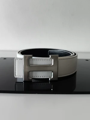 H bälte  - Ett bälte med vit utsida och svart insida aldrig använd och väldigt fint 