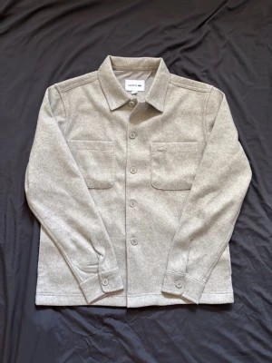 Grå overshirt från Lacoste - Tjena! Säljer nu denna helt nya Lacoste overshirten. Skicket är 10/10 och det är en sällsynt modell. Säljs då den aldrig kom till användning. Vid frågor kontakta gärna!